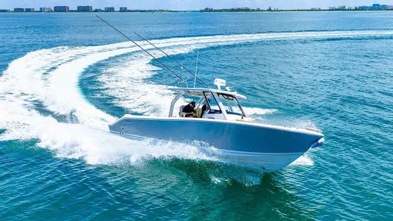 Slide: The Image of Dynamic Bow View in Action The 2019 Pursuit 328, Orcabessa, cuts effortlessly through the water, showcasing its sleek hull design and agile maneuverability. This impressive vessel is equipped with robust fishing rods and a modern helm, set against a backdrop of vibrant blue waters. - 7095052