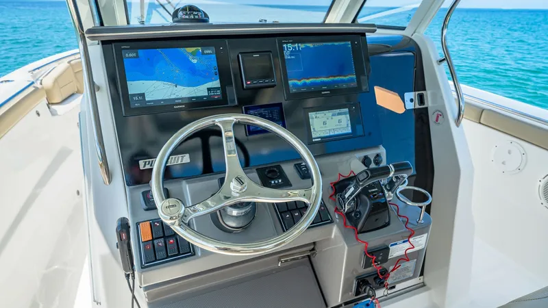 Slide: The Image of Helm Station with Advanced Electronics This helm station on the 2019 Pursuit 328 Orcabessa features state-of-the-art navigation and control systems. The sleek design includes a modern steering wheel, digital displays for navigation, and an ergonomic layout for easy access to controls. The blen - 7095038