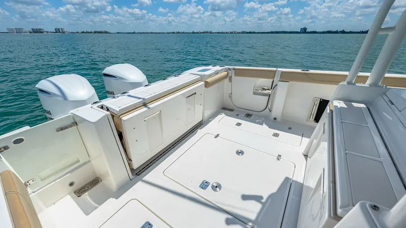 Slide: The Image of Spacious Aft Deck with Storage The aft deck of the 2019 Pursuit 328, Orcabessa, offers a spacious and functional layout perfect for fishing or leisure activities. It features ample storage compartments, sleek white finishes, and easy access to the twin outboard engines. The clean desig - 7095027