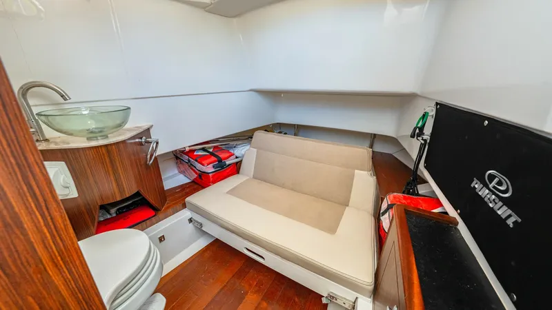 Slide: The Image of Compact Cabin with Seating Area This inviting cabin aboard the 2019 Pursuit 328, Orcabessa, features a versatile seating area that doubles as a sleeping space. The warm wood flooring complements the modern fixtures, including a stylish glass sink and practical countertop. The compact ye - 7095047