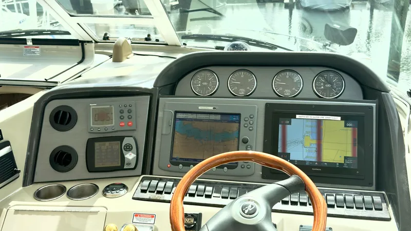 Slide: The Image of Helm Station with Navigation Displays The helm station of the 2006 Sea Ray 40 Motor Yacht 'Knot on Call' showcases a well-equipped command center. It features dual navigation displays, a wooden steering wheel, and an array of analog gauges for precise control and monitoring. The expansive win - 7150629