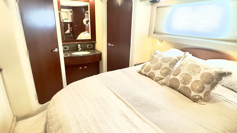 Slide: The Image of Master Stateroom with Ensuite Vanity The master stateroom of the 2006 Sea Ray 40 Motor Yacht features a spacious, well-appointed sleeping area with a plush, cream-colored bed. The room is accented by rich wood cabinetry and a sleek, integrated vanity with a mirror and sink, offering both sty - 7150650