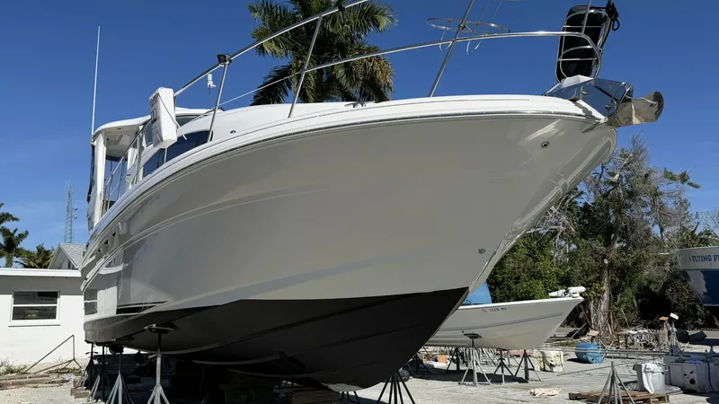 Slide: The Image of Bow View in Dry Dock This image showcases the sleek bow of the 2006 Sea Ray 40 Motor Yacht, 'Knot on Call', elevated in dry dock. The vessel's smooth lines and robust hull design are accentuated, providing a clear view of its impressive craftsmanship. The clean, white exterio - 7150660