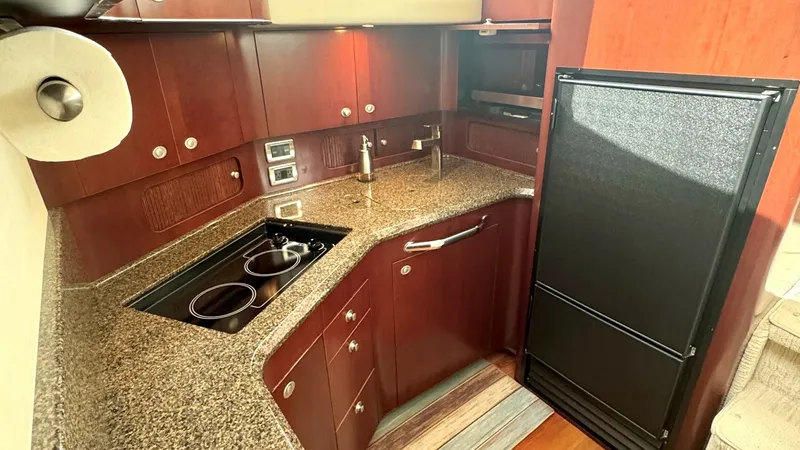 Slide: The Image of Galley with Modern Amenities This well-appointed galley features sleek granite countertops and rich wood cabinetry, offering both functionality and elegance. Equipped with a dual-burner cooktop and a spacious refrigerator, it ensures convenience for onboard dining. The integrated lig - 7150642
