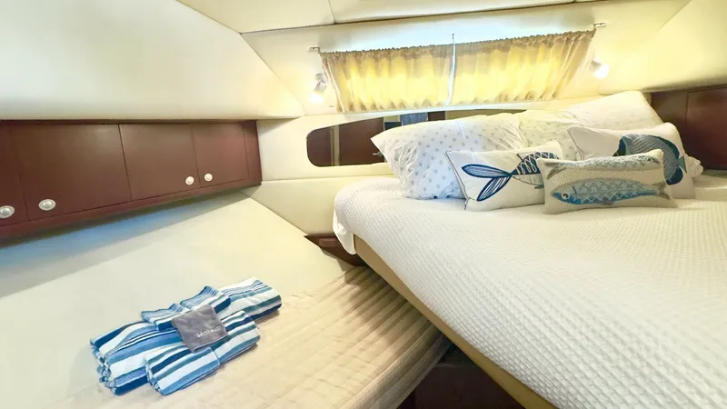 Slide: The Image of Cozy Forward Stateroom with Double Berth This inviting forward stateroom on the 2006 Sea Ray 40 Motor Yacht features a comfortable double berth, adorned with plush pillows and a stylish bedspread. The space is enhanced by warm wood cabinetry offering ample storage, and soft, ambient lighting tha - 7150645