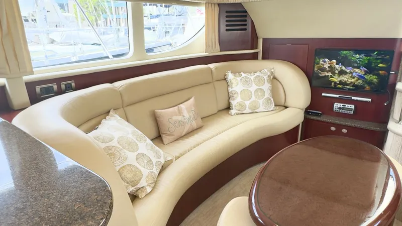 Slide: The Image of Luxurious Salon with Curved Seating The salon of the 2006 Sea Ray 40 Motor Yacht features an elegant curved seating arrangement upholstered in soft beige leather, complemented by decorative throw pillows for added comfort. Large windows provide ample natural light and picturesque views, enh - 7150638