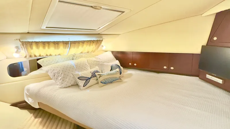 Slide: The Image of Cozy Forward Stateroom The forward stateroom of the 2006 Sea Ray 40 Motor Yacht offers a serene retreat, featuring a plush double berth adorned with tasteful nautical-themed pillows. Warm wood paneling and ambient lighting create a welcoming atmosphere, while ample storage is s - 7150644