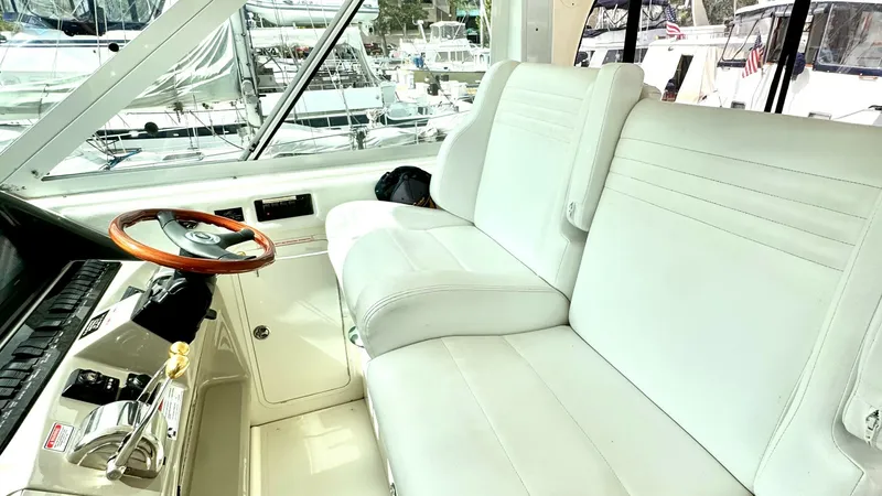 Slide: The Image of Helm Station with Dual Seating The helm station of the 2006 Sea Ray 40 Motor Yacht features a spacious dual seating area with plush white upholstery, providing comfort for the captain and a companion. The elegant wooden steering wheel and well-organized control panel offer a sophistica - 7150627