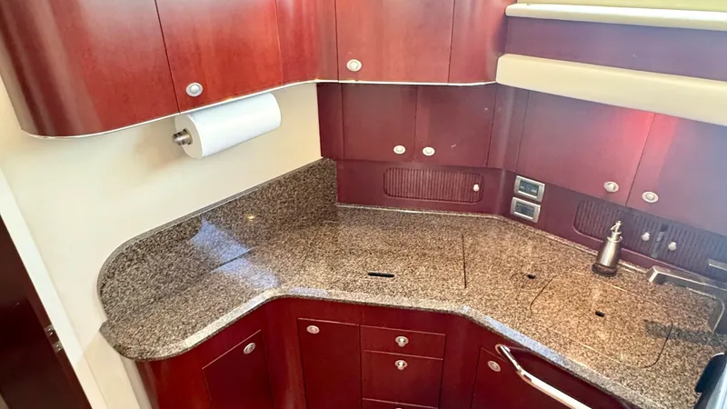 Slide: The Image of Galley with Granite Countertops This elegant galley features stunning granite countertops, offering both style and durability. The rich wood cabinetry provides ample storage, complemented by modern fixtures and a sleek design. Natural light floods the space through a nearby window, enha - 7150641