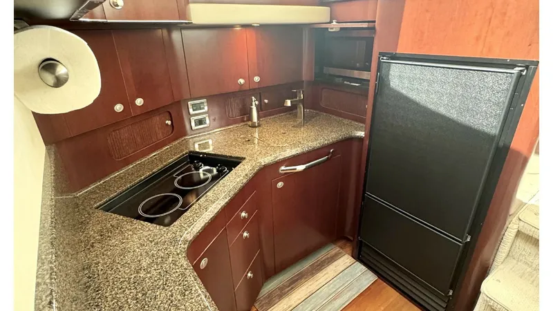 Slide: The Image of Galley with Modern Appliances This well-appointed galley features sleek granite countertops and rich wooden cabinetry, providing both functionality and elegance. Equipped with a built-in cooktop and a spacious refrigerator, it ensures you're ready for gourmet meals at sea. The ample s - 7150623