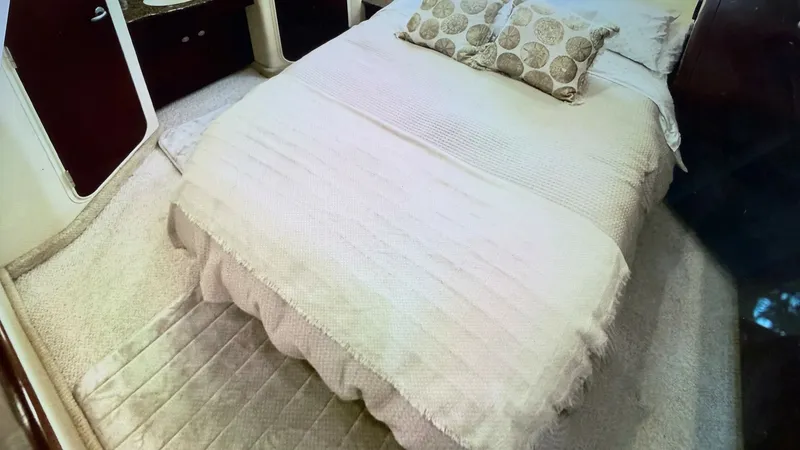 Slide: The Image of Master Stateroom with Ensuite This inviting master stateroom features a plush queen-sized bed, complemented by elegant bedding and accent pillows. The space is thoughtfully designed with warm wood finishes and soft carpeting, creating a cozy retreat. An ensuite bathroom adds convenien - 7150651