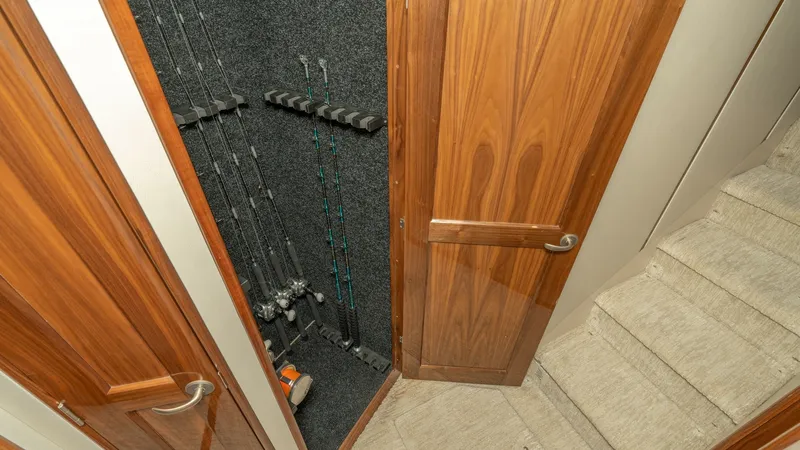 Slide: The Image of Fishing Rod Storage Compartment This image showcases the dedicated fishing rod storage compartment aboard the 2017 Viking 55 Convertible. The neatly arranged rods are securely held in place within a carpeted alcove, designed for easy access and organization. The wooden cabinetry adds a - 7180042
