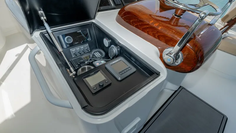 Slide: The Image of Helm Console with Navigation Instruments This image showcases the helm console of the 2017 Viking 55 Convertible, highlighting its advanced navigation instruments. The console features a sleek, open compartment housing essential gauges and digital displays for precise control. The polished woode - 7180048