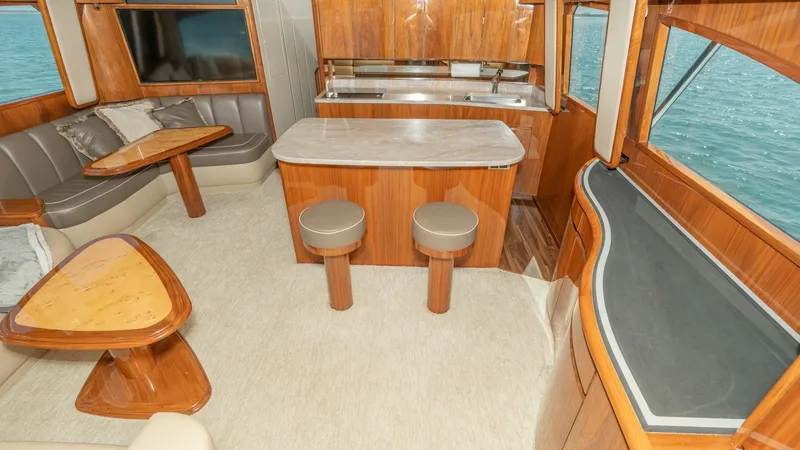 Slide: The Image of Spacious Salon with Dining Area This inviting salon on the 2017 Viking 55 Convertible features elegant wood finishes and ample seating for relaxation and entertainment. The open layout includes a dining area with a plush L-shaped sofa and a high-gloss table, while the bar area provides - 7180026