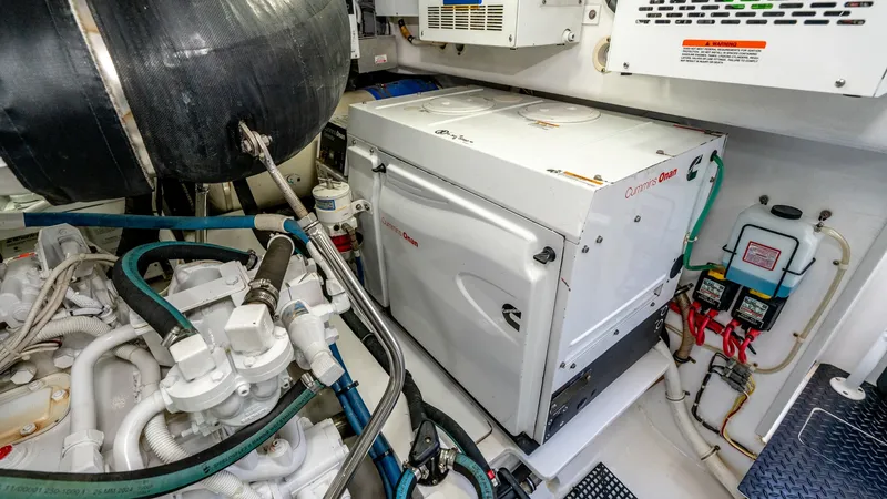 Slide: The Image of Engine Room with Generator The engine room of the 2017 Viking 55 Convertible showcases a well-organized layout featuring a robust Cummins Onan generator. The space is efficiently designed for optimal access to critical components, ensuring ease of maintenance. High-quality material - 7180075