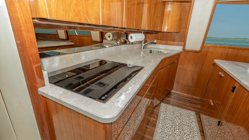 Slide: The Image of Galley with Modern Appliances The galley of the 2017 Viking 55 Convertible showcases elegant wooden cabinetry and sleek countertops. Equipped with a modern stovetop and ample storage, this space is both functional and stylish. Large windows provide natural light and a scenic view, enh - 7180033