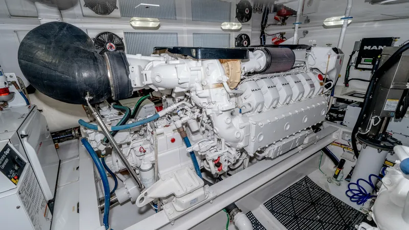 Slide: The Image of Engine Room with MAN Engine This image showcases the pristine engine room of the 2017 Viking 55 Convertible, featuring a powerful MAN engine. The space is meticulously organized, highlighting advanced engineering and ample room for maintenance. Bright lighting and clean installation - 7180070