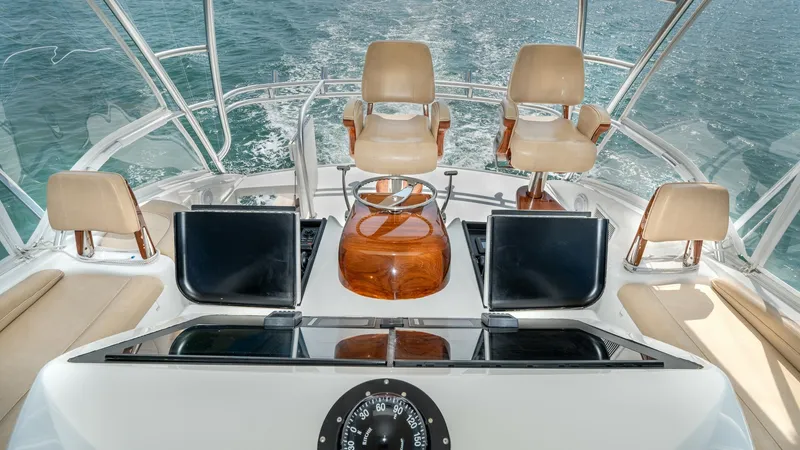 Slide: The Image of Flybridge Helm with Seating Arrangement This image showcases the flybridge helm of the 2017 Viking 55 Convertible, featuring three plush captain's chairs. The helm is equipped with state-of-the-art navigation displays and a classic compass, ensuring precise control and easy navigation. The surr - 7180056