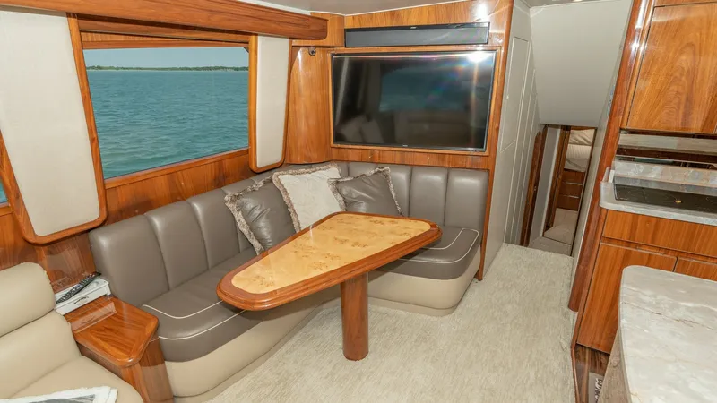 Slide: The Image of Salon Lounge with Entertainment System The salon of the 2017 Viking 55 Convertible features a plush seating area with a custom wooden table, perfect for relaxed gatherings. Rich wood finishes and neutral upholstery create a warm, inviting ambiance. A large flat-screen TV is mounted on the wall - 7180031