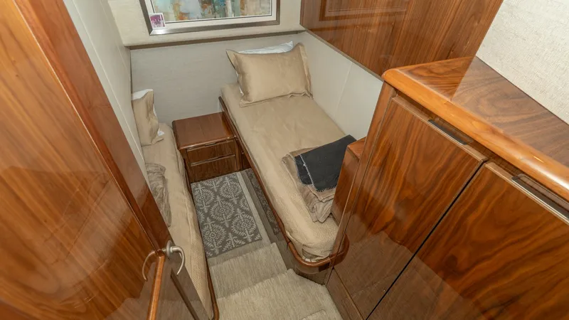 Slide: The Image of Twin Cabin with Wood Finish This cozy twin cabin in the 2017 Viking 55 Convertible features rich wood paneling that exudes warmth and elegance. The twin beds are arranged for optimal space utilization, complemented by a stylish area rug and ample natural light from the window. The h - 7180037
