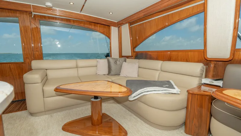 Slide: The Image of Luxurious Salon with Ocean Views This elegant salon aboard the 2017 Viking 55 Convertible features plush, cream-colored leather seating that curves around a polished wooden coffee table. Large windows offer panoramic ocean views, enhancing the bright and inviting atmosphere. The high-qua - 7180030