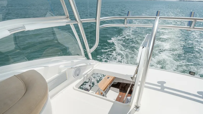 Slide: The Image of Flybridge Helm and Seating Area This image showcases the flybridge helm of the 2017 Viking 55 Convertible, offering a commanding view of the open waters. The area is equipped with polished stainless steel railings and a comfortable helm chair, providing both functionality and comfort. T - 7180058