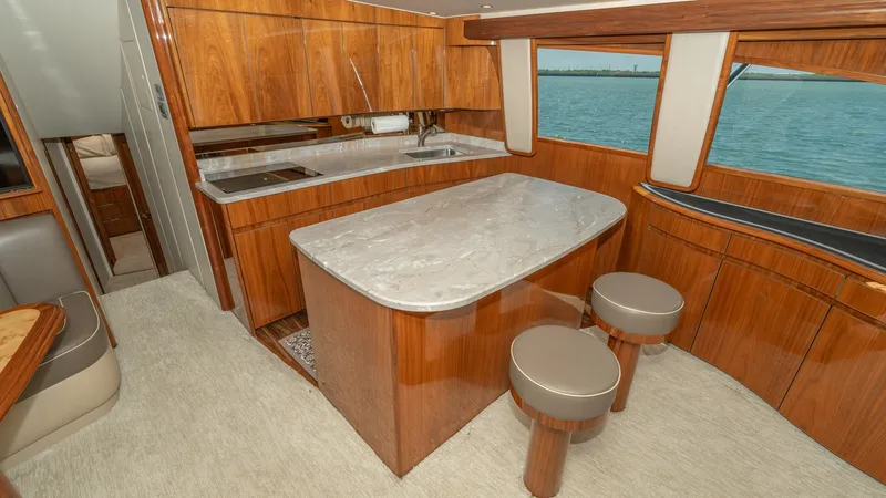 Slide: The Image of Galley and Dinette Area This elegant galley on the 2017 Viking 55 Convertible features rich wood cabinetry and a sleek marble countertop, offering a luxurious and functional space for meal preparation. The spacious dinette with plush seating provides a comfortable area for dinin - 7180036