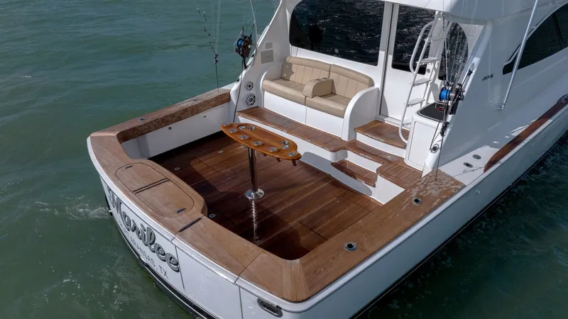Slide: The Image of Spacious Aft Deck with Seating The aft deck of the 2017 Viking 55 Convertible offers a spacious area perfect for relaxation and fishing. Featuring elegant teak decking and a comfortable built-in bench, this area is designed for both leisure and functionality. The well-appointed layout - 7180084