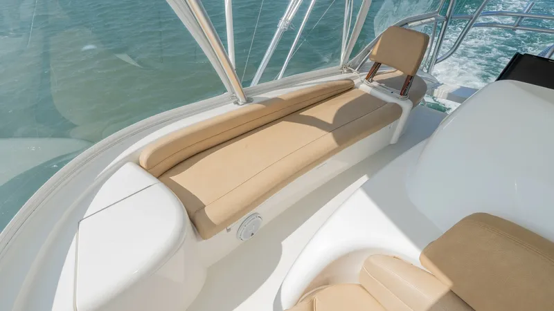 Slide: The Image of Flybridge Seating Area This image showcases the comfortable flybridge seating area of the 2017 Viking 55 Convertible. The spacious layout features plush tan cushions that provide an inviting space for relaxation while enjoying panoramic views. The surrounding clear enclosure en - 7180051