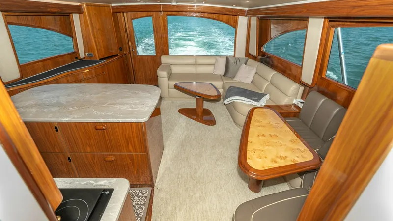 Slide: The Image of Luxurious Salon with Open Layout The salon of the Viking 55 Convertible features an inviting open layout with plush L-shaped seating and elegant wood finishes. Large windows offer panoramic views, enhancing the natural light and airy feel of the space. The well-appointed galley includes - 7180028