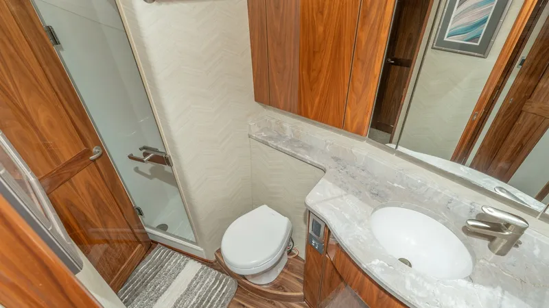 Slide: The Image of Elegant Yacht Bathroom with Shower This well-appointed bathroom on the 2017 Viking 55 Convertible features a sleek, modern design with high-quality finishes. The space includes a spacious glass-enclosed shower, a stylish marble countertop with an integrated sink, and rich wooden cabinetry - 7180043