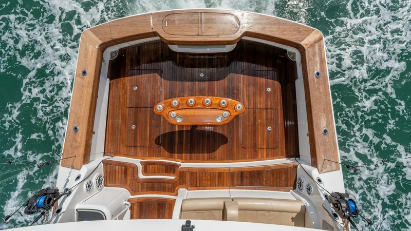 Slide: The Image of Aft Deck with Teak Flooring This image showcases the elegant aft deck of the 2017 Viking 55 Convertible, featuring rich teak flooring. The spacious area is highlighted by a polished fighting chair, ideal for fishing enthusiasts. The deck's sleek design and quality materials offer bo - 7180061