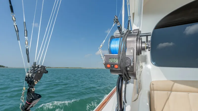 Slide: The Image of Fishing Setup on Aft Deck This image showcases the fishing setup on the aft deck of the 2017 Viking 55 Convertible. The robust reel system is prominently displayed, equipped with a digital line counter for precision. The comfortable seating and expansive views highlight the vessel - 7180065