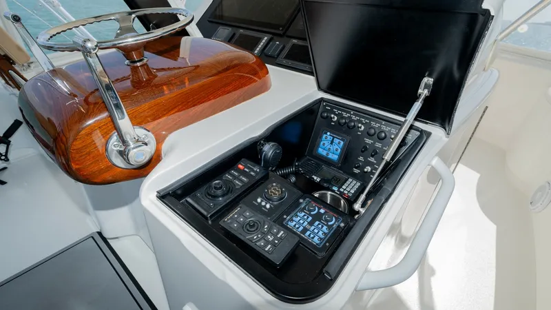 Slide: The Image of Helm Station with Electronics Console The helm station of the 2017 Viking 55 Convertible features a sophisticated electronics console, showcasing advanced navigation and communication systems. The polished wooden steering wheel complements the sleek design, offering both functionality and sty - 7180049