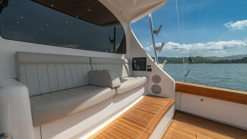 Slide: The Image of Cockpit Seating Area with Teak Decking This image showcases the elegant cockpit seating area of the 2024 Viking 64 Convertible. The plush, upholstered seating is designed for comfort, complemented by the warm tones of the teak decking. Surrounded by stunning views, this space offers a perfect - 7162578
