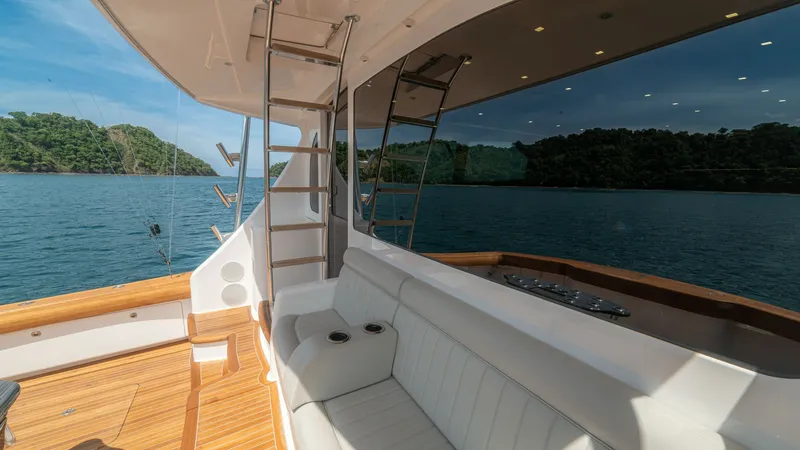 Slide: The Image of Aft Deck Seating with Scenic View This inviting aft deck on the 2024 Viking 64 Convertible 'Fish Tank' features plush white seating perfect for relaxation while enjoying the stunning ocean views. The teak flooring adds a touch of elegance, complemented by the polished stainless-steel ladd - 7162580