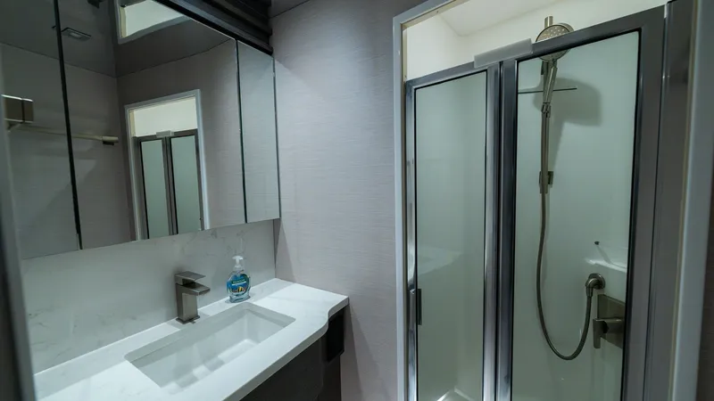 Slide: The Image of Elegant Yacht Bathroom with Shower This modern bathroom aboard the 2024 Viking 64 Convertible features a sleek countertop with an integrated sink and stylish fixtures. The glass-enclosed shower offers a luxurious experience, complemented by soft ambient lighting. High-quality finishes and - 7162565