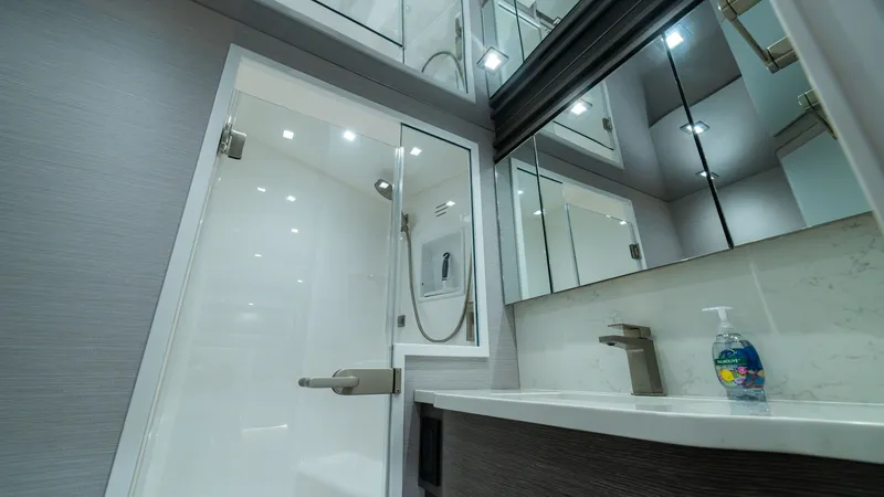 Slide: The Image of Luxurious Ensuite Bathroom This elegant ensuite bathroom on the 2024 Viking 64 Convertible features modern fixtures and a sleek design. The spacious shower area is enclosed in glass, complemented by stylish cabinetry and a chic marble countertop. Ample lighting and mirrors enhance - 7162576