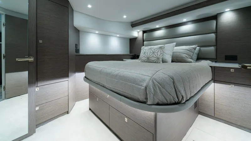 Slide: The Image of Luxurious Master Stateroom The master stateroom aboard the 2024 Viking 64 Convertible features a plush, elevated bed with elegant bedding, providing a restful retreat. Rich wood finishes and ambient recessed lighting create a warm, inviting atmosphere. Ample storage surrounds the s - 7162568