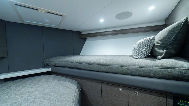 Slide: The Image of Guest Cabin with Twin Berths The guest cabin on the 2024 Viking 64 Convertible offers twin berths with plush grey upholstery, providing a comfortable retreat for guests. The sleek cabinetry below offers ample storage, while recessed lighting enhances the modern and cozy atmosphere. T - 7162563