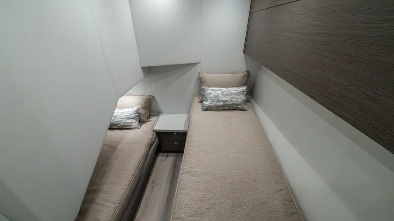 Slide: The Image of Guest Cabin with Twin Berths This cozy guest cabin on the 2024 Viking 64 Convertible features twin berths, offering comfort and style. The neutral tones and soft lighting create a serene atmosphere, complemented by the elegant wood finishes. Practical storage solutions and plush bedd - 7162557