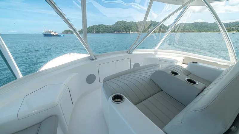 Slide: The Image of Flybridge Seating with Ocean View This image showcases the luxurious flybridge seating area of the 2024 Viking 64 Convertible. The plush, contoured seats offer built-in cup holders, ensuring comfort and convenience for guests. Surrounded by expansive windows, this space provides breathtak - 7162596