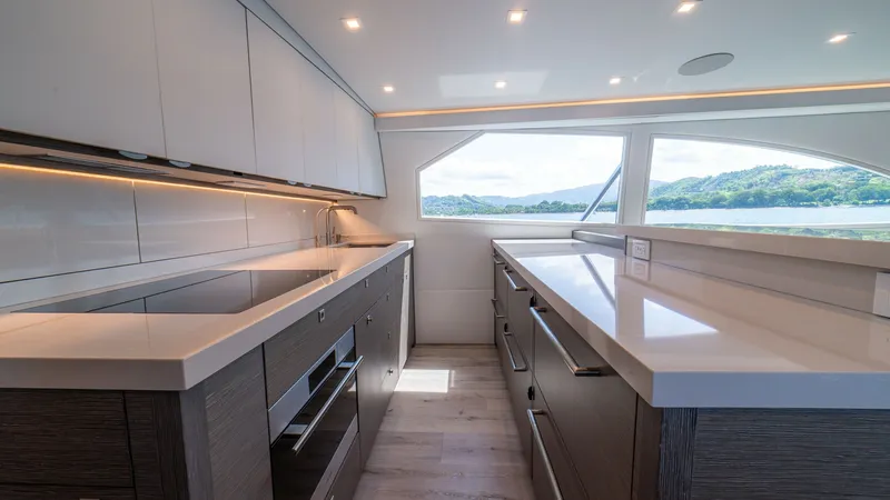 Slide: The Image of Modern Galley with Scenic View This sleek and contemporary galley on the 2024 Viking 64 Convertible features polished countertops and ample storage with elegant cabinetry. Natural light floods the space through large windows, offering breathtaking views of the surrounding waters. The s - 7162550