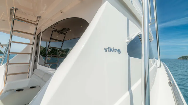 Slide: The Image of Starboard Side Deck with Ladder This image showcases the sleek starboard side deck of the 2024 Viking 64 Convertible, featuring polished stainless steel railings and a sturdy ladder leading to the flybridge. The elegant curves of the hull are complemented by the pristine white finish, p - 7162588