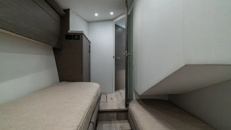Slide: The Image of Guest Cabin with Twin Berths This cozy guest cabin on the 2024 Viking 64 Convertible features twin berths, offering a comfortable and inviting space for guests. The room is elegantly designed with soft, neutral-toned upholstery and subtle wood accents, creating a warm and relaxing at - 7162558