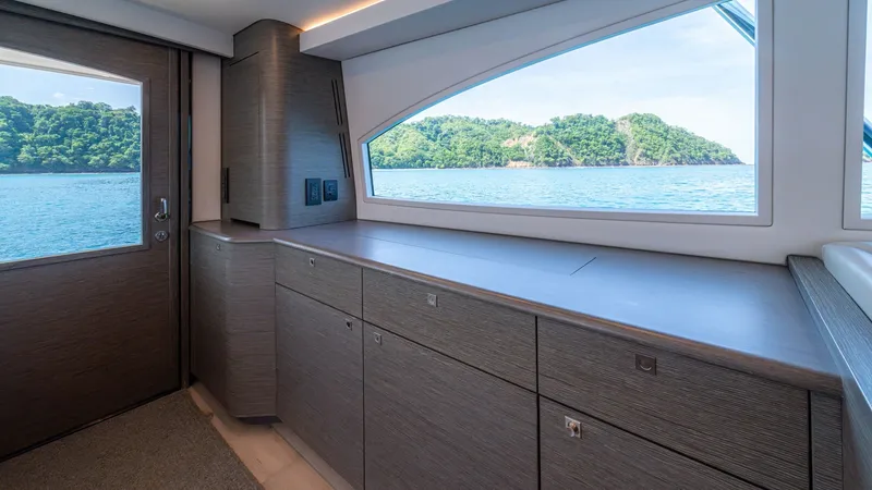 Slide: The Image of Galley with Ocean View The starboard galley of the 2024 Viking 64 Convertible features sleek cabinetry with ample storage, perfect for culinary adventures at sea. Expansive windows flood the space with natural light and offer stunning ocean views, enhancing the onboard experien - 7162553
