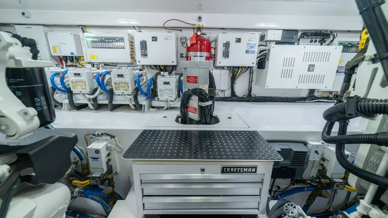 Slide: The Image of Engine Room with Electrical Systems This image showcases the meticulously organized engine room of the 2024 Viking 64 Convertible, featuring advanced electrical systems. Prominent is the Craftsman tool chest, surrounded by neatly arranged wiring and control units, ensuring efficient mainten - 7162607