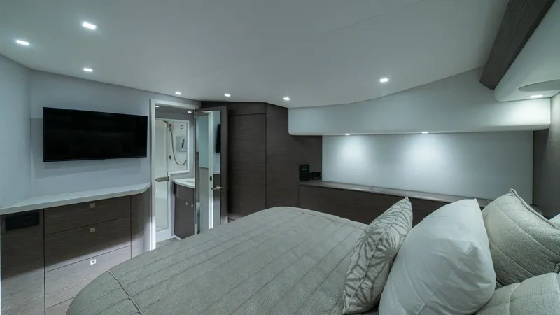Slide: The Image of Elegant Master Stateroom The master stateroom of the 2024 Viking 64 Convertible features a luxurious, well-lit space with modern finishes. The room is equipped with a large bed, stylish cabinetry, and a wall-mounted TV for entertainment. The sleek design and ambient lighting crea - 7162570
