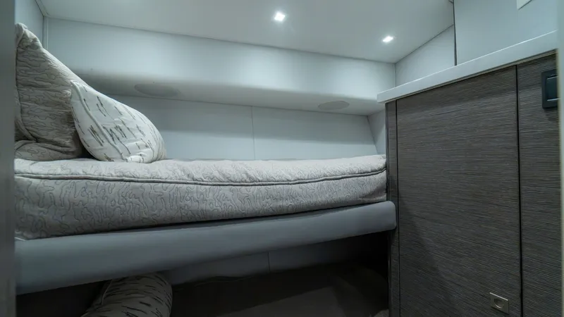 Slide: The Image of Guest Stateroom with Bunk Beds This cozy guest stateroom features comfortable bunk beds, perfect for accommodating additional guests. The modern design includes sleek cabinetry with a wood finish, adding a touch of elegance to the space. Recessed lighting enhances the room's ambiance, - 7162566