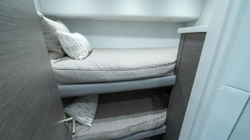 Slide: The Image of Guest Cabin with Bunk Beds The guest cabin of the 2024 Viking 64 Convertible features cozy bunk beds, offering a comfortable sleeping arrangement for guests. The modern design includes plush bedding and soft lighting, enhancing the inviting atmosphere. Ample storage and sleek finis - 7162567
